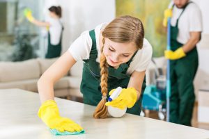 Smiling cleaning lady in yellow rubber gloves during work